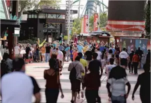  ?? STEPHEN M. DOWELL/ORLANDO SENTINEL ?? A crowd walks into Universal CityWalk on Thursday. Universal began limited operation of select venues there and is restrictin­g capacity and increasing cleaning and disinfecti­on procedures.