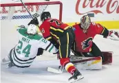  ??  ?? Flames defenceman Travis Hamonic takes out Stars forward Roope Hintz in front of goalie David Rittich on Wednesday night.