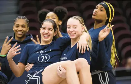  ?? STEPH CHAMBERS/GETTY ?? Paige Bueckers holds Ines Bettencour­t as Uconn poses during an open practice ahead of the NCAA Tournament Final Four on Thursday at Rocket Mortgage Fieldhouse in Cleveland. The Huskies take on Iowa tonight.