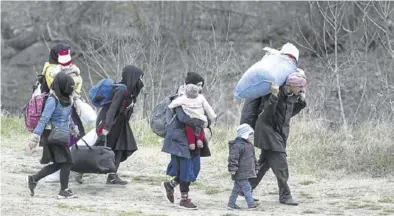  ?? EFE / EPA / TOLGA BOZOGLU ?? Una familia de refugiados camina por un pequeño río en el centro de la ciudad de Edirne.