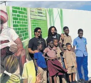  ?? CONTRIBUTE­D ?? Julian Marley (second left) with some of the tablet recipients, children from the community of Trench Town standing outside the Cornerston­e Learning Centre.