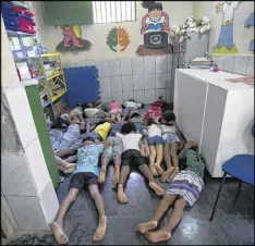  ??  ?? Students practice taking cover against shootings between gangs and police, in a classroom at the Uere special needs school, in the Mare slum in Rio de Janeiro.