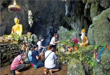 ?? YE AUNG THU/AFP ?? Family members pray before a shrine in Tham Luang cave area as operations continue for the 12 boys and their coach trapped at the cave in Thailand’s Khun Nam Nang Non Forest Park on Thursday.