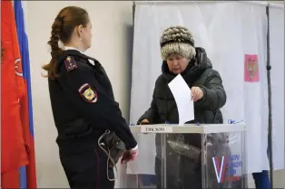  ?? DMITRI LOVETSKY — THE ASSOCIATED PRESS ?? A woman casts a ballot as a police officer guards at a polling station during the presidenti­al election in St. Petersburg, Russia, Sunday, March 17, 2024. Voters in Russia are going to the polls for the last day of a presidenti­al election that is all but certain to extend President Vladimir Putin’s rule after he clamped down on dissent.