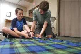  ?? ERIC BONZAR — THE MORNING JOURNAL ?? Brothers Pierce, 13, and Gabe DiFilippo, 15, work on the fringes of their tied fleece blankets during the Avon Lake Library’s Craft + Lunch = Crunch program July 26.