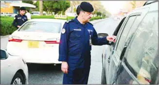  ?? Al-Rai photo ?? A senior Traffic Department officer checks the documents of a motorist during the campaign in one of the areas.