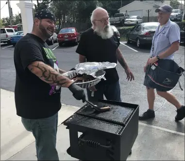  ?? MICHAEL FITZPATRIC­K — THE MORNING JOURNAL ?? Noel Santiago works at the grill as Dominic Manges and Paul Callahan look on. Santiago was grilling hotdogs as part of a picnic at Firelands Retirement Center to celebrate recent improvemen­ts made at the facility