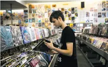  ??  ?? James Robinson of Newcastle, England, looks through the vinyl section at Amoeba. Vinyl records merit a big part of the store; the CD area has shrunk.