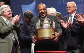  ?? JAMIE-ANDREA YANAK / AP, FILE ?? Jim Brown, center, picks up a trophy presented by NFL Commission­er Paul Tagliabue, to the members of the Cleveland Browns 1964 Championsh­ip Team, at Severance Hall in Cleveland on Sept. 10, 2004. At left is Bernie Parish, and at right Paul Wiggin. The original trophy presented to the team after their 1964 victory over the Baltimore Colts is in the possession of the Green Bay Packers, who were the 1965 Championsh­ip Team.