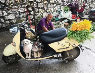  ?? — AFP ?? This man in Yulin, China, has pet dogs that are obviously well-looked after and loved, but at the same time, he has no quarrel with the restaurant behind him which serves dog meat. While attitudes are changing, it will take time to get everyone on board, say activists.