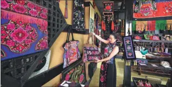  ?? YANG ZONGYOU / XINHUA ?? Luo Jun (above, right) displays a handbag featuring the embroidery of the Yi ethnic group (below) in her workshop at Chuxiong Yi autonomous prefecture in Southwest China’s Yunnan province on August 14, 2016. As a female entreprene­ur of the Yi ethnic...