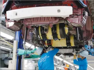  ?? The Associated Press ?? Workers at a Toyota plant install hydrogen-storage tanks, in yellow, into a Mirai fuel cell vehicle.Toyota, maker of the Prius, believes fuel-cell vehicles may be the future.