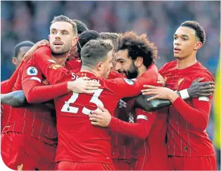  ??  ?? Mo Salah is surrounded by team-mates after opening the scoring