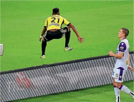  ?? PHOTO: PHOTOSPORT ?? Wellington Phoenix’s Roy Krishna jumps over the advertisin­g hoarding as he celebrates a goal against Perth Glory.