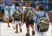  ??  ?? Boys sport identical backpacks Sunday from the Issa Back 2 School Drive. Kids also could play in bounce castles, try a rock climbing wall and participat­e in other fun activities.