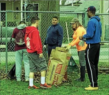  ?? MARK ROBARGE — MROBARGE@TROYRECORD.COM ?? Troy City Council member Erin Sullivan-Teta, second from right, works with a group of volunteers from the Lansingbur­gh High School football program to rake and collect trash in 112th Street Park during a citywide cleanup program on Saturday to mark...