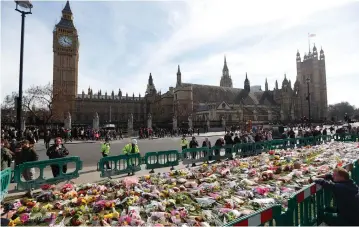  ?? (Reuters) ?? WORKMEN FENCE off floral tributes in Parliament Square, following the attack in Westminste­r earlier in the week, in London.