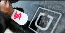  ?? GENE J. PUSKAR — THE ASSOCIATED PRESS FILE ?? A Lyft logo is installed on a car next to an Uber sticker in Pittsburgh. Uber and Lyft drivers might seem well-insured, however, a crucial gap leaves drivers at risk if they have an accident at the wrong time.