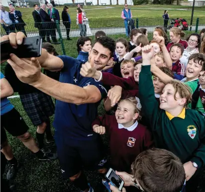  ??  ?? Tiernan O’Halloran poses for pictures with students during Connacht’s visit to Seamount College, Kinvara