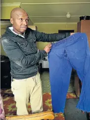  ?? Picture: EUGENE COETZEE ?? IMPACT TEAR: Mthandazo Dingana with the pants that were torn when a forklift pinned him to a rubbish skip