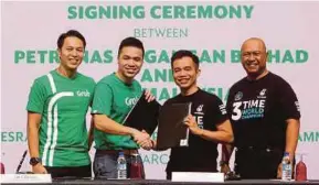  ?? EIZAIRI SHAMSUDIN
PIC BY ?? Grab Malaysia country head Sean Goh (second from left) exchanging documents with Petronas Dagangan Bhd (PetDag) head of retail business Aadrin Azly at a signing ceremony in Kuala Lumpur yesterday. With them are PetDag managing director and chief...