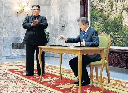  ?? Picture: REUTERS ?? MAKING HISTORY: South Korean President Moon Jae-in signs a guest book as North Korean leader Kim Jong Un applauds before their summit at the truce village of Panmunjom, North Korea on Saturday