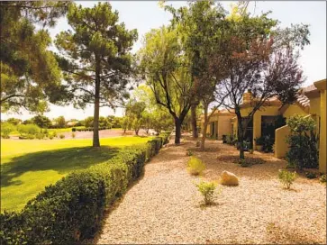  ?? Patrick T. Fallon AFP/Getty Images ?? HOMES SIT next to a golf course in Las Vegas where grass lawns were dug up as a way to conserve water. Las Vegas has dramatical­ly shrunk its water footprint over the last two decades using a variety of methods.