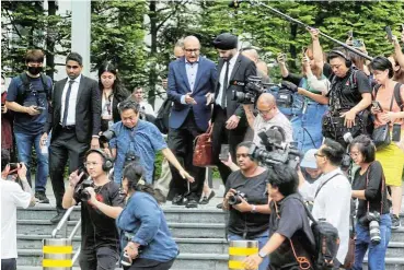 ?? /Reuters ?? Not me: S Iswaran, Singapore’s former transport minister, centre, arrives at the State Courts in Singapore on Thursday. He appeared on a total of 27 charges, but has rejected them and says he will fight to clear his name.