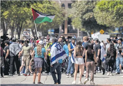  ?? ?? Pro-Israeli demonstrat­ors look at as pro-Palestinia­n demonstrat­ors protest on the campus of UCLA on Sunday.