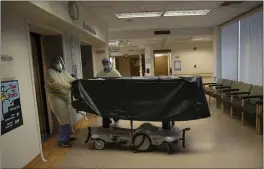  ?? JAE C. HONG — THE ASSOCIATED PRESS FILE ?? Hospital staff members enter an elevator with the body of a COVID-19victim on a gurney at St. Jude Medical Center in Fullerton.