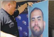  ?? Irfan Khan Los Angeles Times ?? GARDEN GROVE Police Cpl. Charles Starnes displays photos of murder suspect Zachary Castaneda.