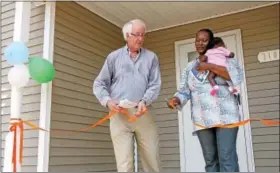  ?? DIGITAL FIRST MEDIA FILE PHOTO ?? Patricia Nnah, holding her 10-week-old daughter, Lukeni, cuts the ribbon on her new home in North Hills with assistance from Gary Lasher, vice president of the board of Habitat for Humanity in Montgomery County.