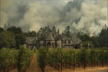  ?? JAE C. HONG — THE ASSOCIATED PRESS ?? A wildfire burns behind a winery Saturday in Santa Rosa Fire crews made progress this week in their efforts to contain the massive wildfires in California wine country, but officials say strong winds are putting their work to the test.