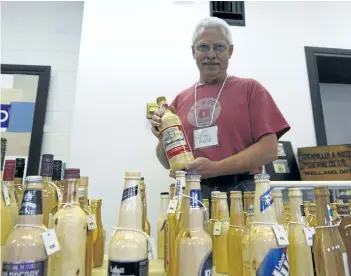  ?? DAVE JOHNSON/POSTMEDIA NEWS ?? Jim Pace shows off a wooden bottle of Budweiser he made on Saturday at the Niagara Brewery Collectibl­es Club Trade Show at Welland Historical Museum in Welland.