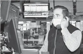  ?? NICOLE PEREIRA/NEW YORK STOCK EXCHANGE ?? A trader works Tuesday at the New York Stock Exchange as a screen displays the Dow reaching a milestone.