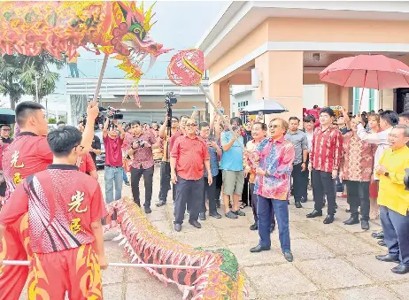  ?? ?? Abang Johari joins in the dragon dance performanc­e, as Wong, on his right, and others look on.