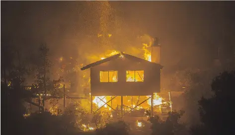  ?? DAVID MCNEW / GETTY IMAGES ?? A structure burns in the early morning hours of Friday near Bonsall, Calif. Strong Santa Ana winds are fanning multiple wildfires in the state.