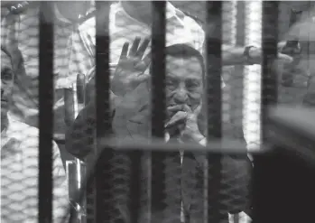  ?? — AP ?? Ousted Egyptian President Hosni Mubarak, sitting in a defendant’s cage with his son Gamal ( left), waves during a court hearing in Cairo on Wednesday.