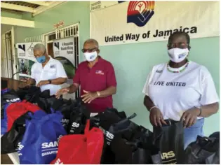  ??  ?? United Way of Jamaica’s Team on location at Noranda Bauxite distributi­ng care packages - CEO Winsome Watkins (l), and volunteers Lance Neita and Enith Williams
