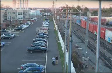  ?? DAN SOKIL — MEDIANEWS GROUP ?? A couple walks a dog down a portion of the Liberty Bell Trail in Lansdale, between the Madison Apartments at left and rail tracks at right, as seen in December 2021.