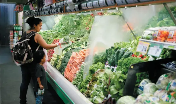  ?? LOS ANGELES COUNTY DEPARTMENT OF PUBLIC HEALTH HANDOUT PHOTO VIA AP ?? A mother shops for fresh produce at Northgate Gonzalez Market on Sept. 28 in Los Angeles. Data released today shows that food insecurity affected one out of three Los Angeles County low-income households.