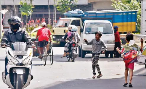  ?? AHMAD KHUSAINI/JAWA POS ?? MEMBAHAYAK­AN SEMUA ORANG: Anak-anak yang bermain layang-layang di jalan raya rentan tertabrak pengendara. Benangnya juga bisa mencelakai pengguna jalan lainnya.