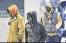  ?? JOHN SPINK / JSPINK@AJC.COM ?? Aggentrice Grier Jr. (center) was bundled up against the cold on Friday morning at Pryor and Wall streets in downtown Atlanta.