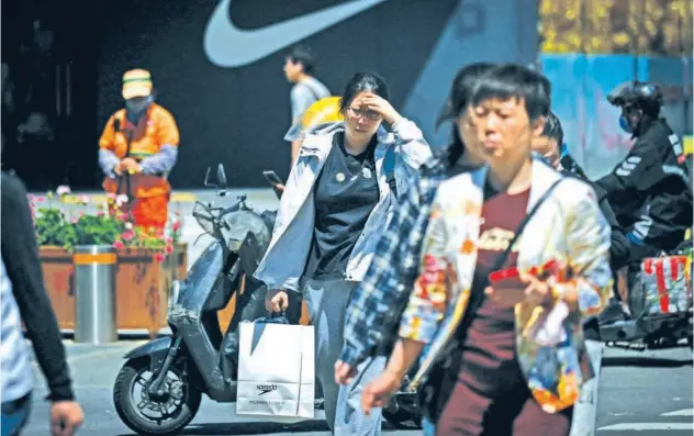  ?? Agence France-presse ?? ↑
People cross a street at a business district in Beijing.