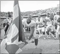  ?? AP/Austin American-Statesman/JAY JANNER ?? Oklahoma defensive end Ogbonnia Okoronkwo plants an Oklahoma flag on the 50-yard line at the Cotton Bowl in Dallas on Saturday after the No. 12 Sooners beat the Texas Longhorns 29-24.