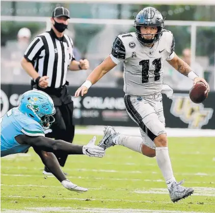  ?? STEPHEN M. DOWELL/ORLANDO SENTINEL ?? UCF quarterbac­k Dillon Gabriel scrambles away from Tulane defensive end Cameron Sample at the Bounce House on Saturday.