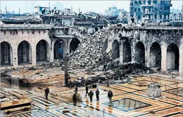 ?? GEORGE OURFALIAN/GETTY-AFP ?? Syrian fighters stroll through a battered mosque Tuesday after retaking Aleppo, the country’s former commercial hub.