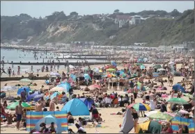  ?? (AP/Andrew Matthews) ?? People crowd the beach Tuesday in Bournemout­h, south England. Prime Minister Boris Johnson announced a rollback of lockdown measures on pubs, cinemas, churches and hair salons starting July 4, and some scientists worry that the move is too hasty.