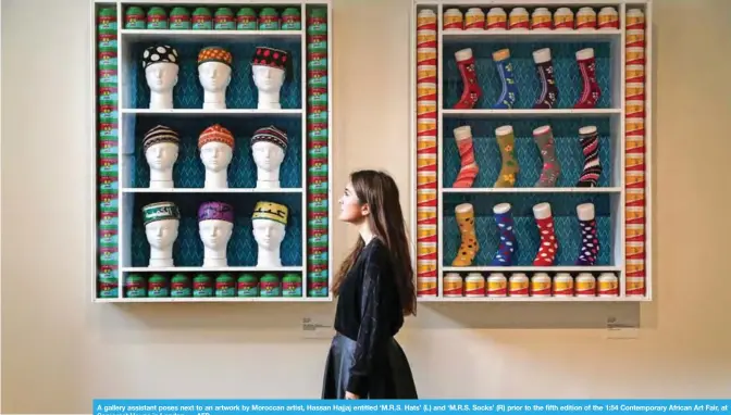  ??  ?? A gallery assistant poses next to an artwork by Moroccan artist, Hassan Hajjaj entitled ‘M.R.S. Hats’ (L) and ‘M.R.S. Socks’ (R) prior to the fifth edition of the 1:54 Contempora­ry African Art Fair, at Somerset House in London. — AFP