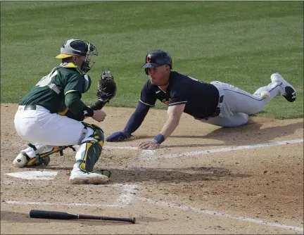  ?? DARRON CUMMINGS — THE ASSOCIATED PRESS ?? The Indians’ Nolan Jones slides in safely at home as the Athletics’ Ronnie Freeman waits for the throw during a 2020spring training game in Mesa, Ariz.